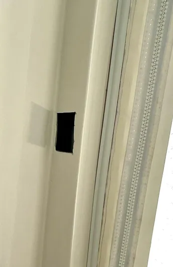 Reel Life Yacht Photos Pics Wall with a small black rectangular hole near a window with blinds.