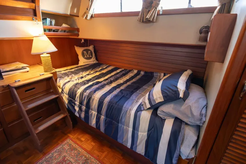 Moonshadow Yacht Photos Pics Cozy cabin interior of 1985 Grand Banks 42 Classic yacht with striped bedding and wooden furnishings.