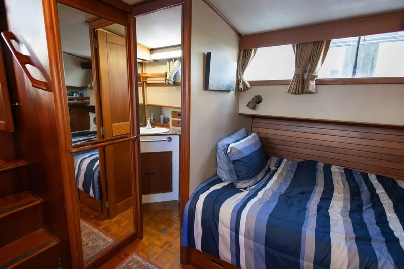 Moonshadow Yacht Photos Pics Cozy cabin interior of 1985 Grand Banks 42 Classic yacht with striped bedding and wooden accents.