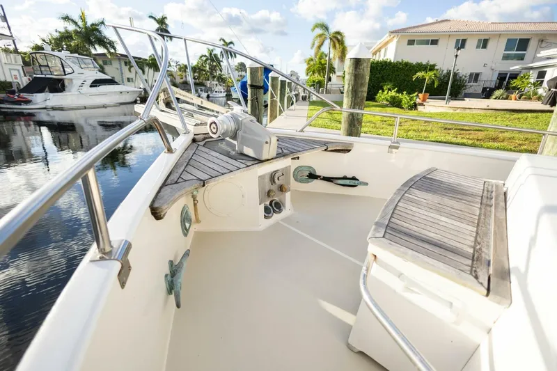 Moonshadow Yacht Photos Pics 1985 Grand Banks 42 Classic yacht deck with wooden seating and railing, docked near waterfront homes.