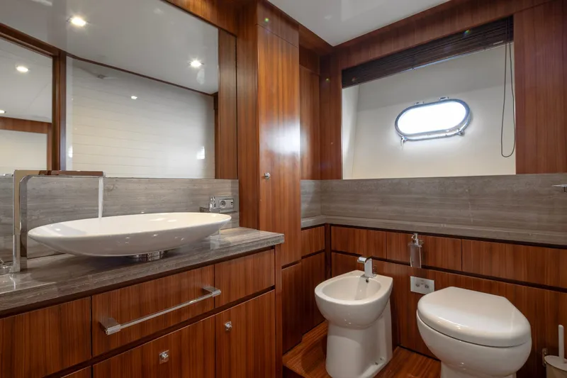  Yacht Photos Pics Luxurious yacht bathroom with wood accents, featuring a sink, toilet, and bidet. Custom Line Navetta 26 Crescendo.