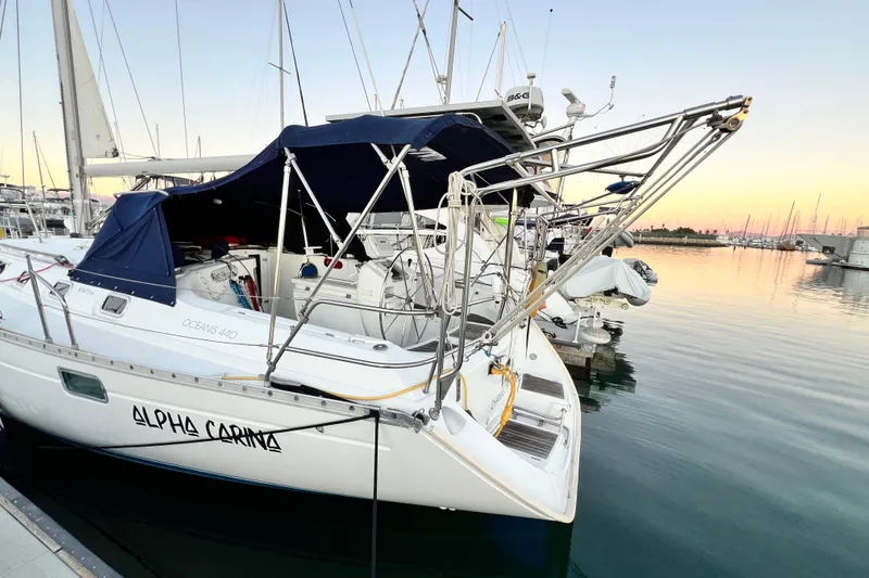 Alpha Carina Yacht Photos Pics 1993 Beneteau Oceanis 440 sailboat docked at sunset, featuring sleek design and blue canopy.