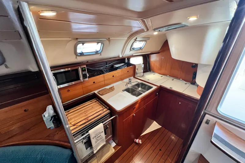 Alpha Carina Yacht Photos Pics Interior of 1993 Beneteau Oceanis 440 yacht kitchen with wood cabinetry and modern appliances.
