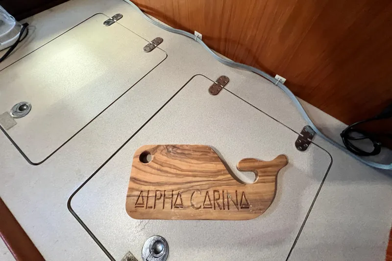 Alpha Carina Yacht Photos Pics Beneteau Oceanis 440 yacht interior with wooden whale-shaped decor labeled "Alpha Carina."