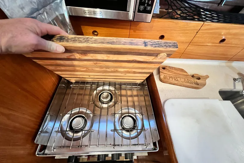 Alpha Carina Yacht Photos Pics Beneteau Oceanis 440 yacht kitchen with a three-burner stove and wooden cover, 1993 model.