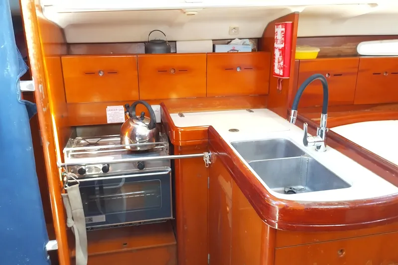  Yacht Photos Pics 2004 Beneteau First 40.7 yacht kitchen with stove, sink, and wooden cabinetry.