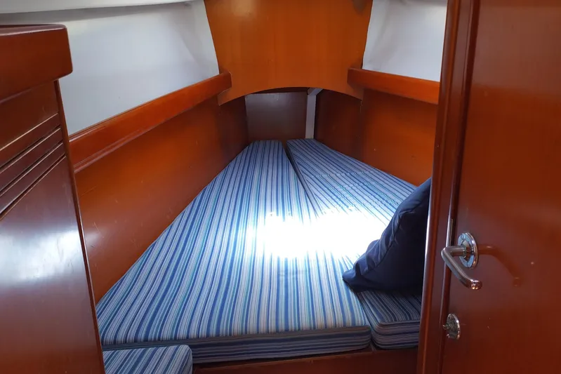  Yacht Photos Pics Cozy cabin interior of 2004 Beneteau First 40.7 with striped bedding and wooden finish.