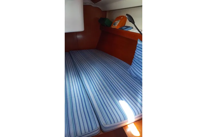  Yacht Photos Pics Interior cabin of 2004 Beneteau First 40.7 with striped bedding and storage shelves.