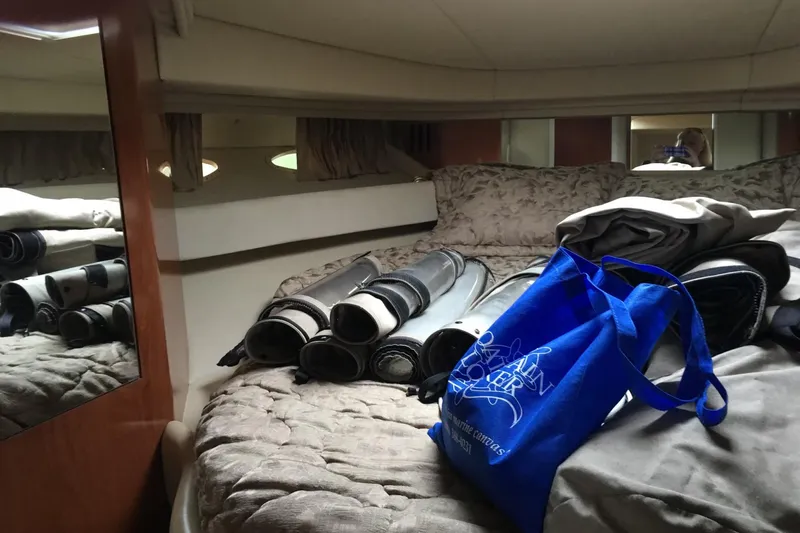 Cap'n Belle Yacht Photos Pics Interior of 2002 Sea Ray 410 Sundancer with bed, rolled mats, and blue bag.