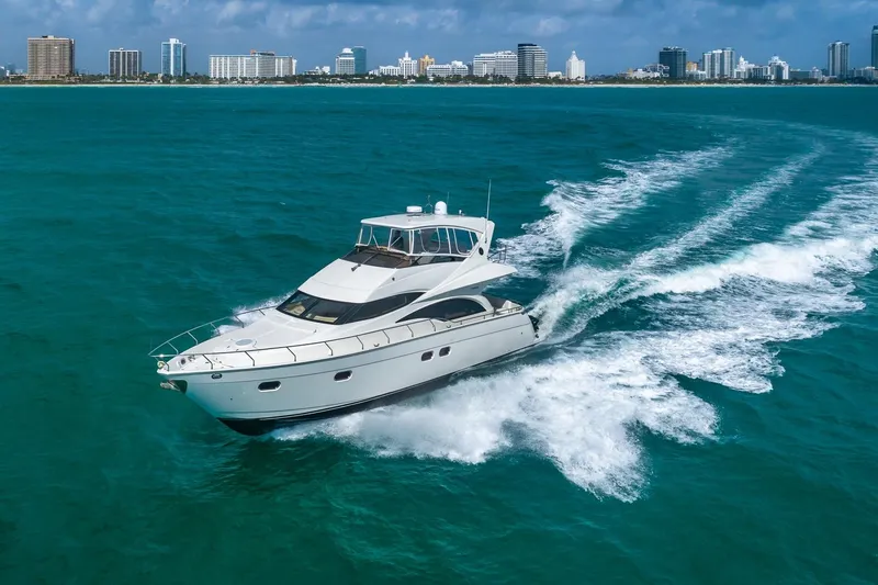  Yacht Photos Pics Luxurious 2005 Marquis 59 yacht cruising in turquoise waters near a city skyline.