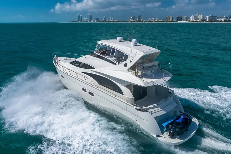  Yacht Photos Pics Luxurious 2005 Marquis 59 yacht cruising on turquoise waters near a city skyline.