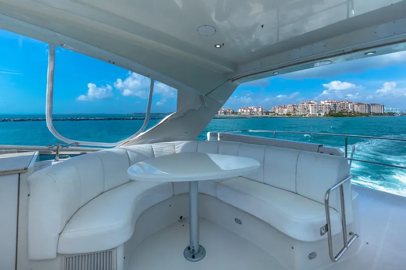  Yacht Photos Pics Luxurious 2005 Marquis 59 yacht interior with white seating, ocean view, and cityscape in the background.