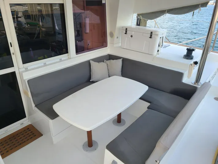 The Next Thing Yacht Photos Pics Lagoon 400 catamaran cockpit with cushioned seating and table, 2010 model, ocean view.