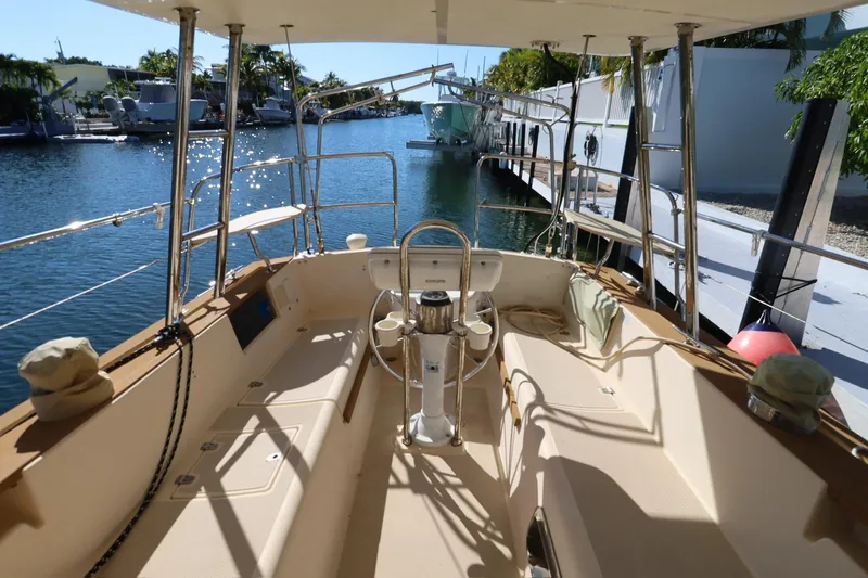 Inspiration Yacht Photos Pics 1989 Island Packet 38 sailboat cockpit with steering wheel, docked by a canal.