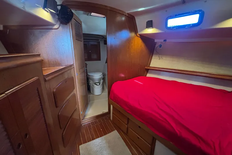 Inspiration Yacht Photos Pics 1989 Island Packet 38 yacht interior with red bedding, wooden cabinetry, and compact bathroom.
