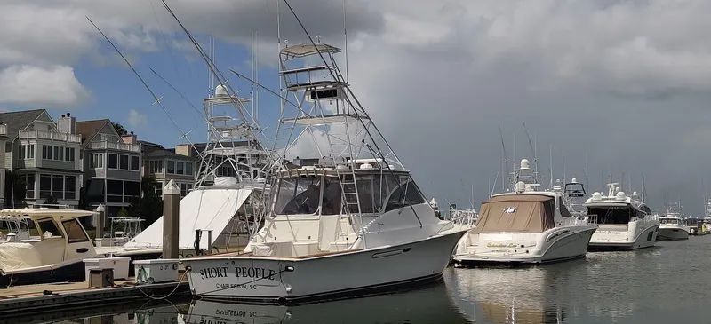 Short People Yacht Photos Pics 1999 Ocean Yachts EXPRESS docked in a marina with other boats under cloudy skies.
