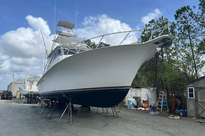 Short People Yacht Photos Pics 1999 Ocean Yachts Sport Fish boat on dry dock, surrounded by trees and equipment.