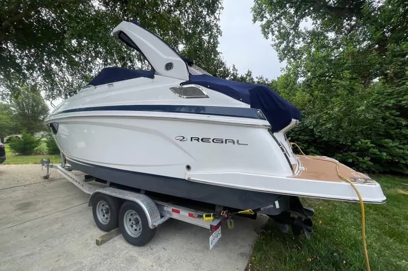  Yacht Photos Pics 2019 Regal 28 Express boat on trailer, parked outdoors with trees in the background.