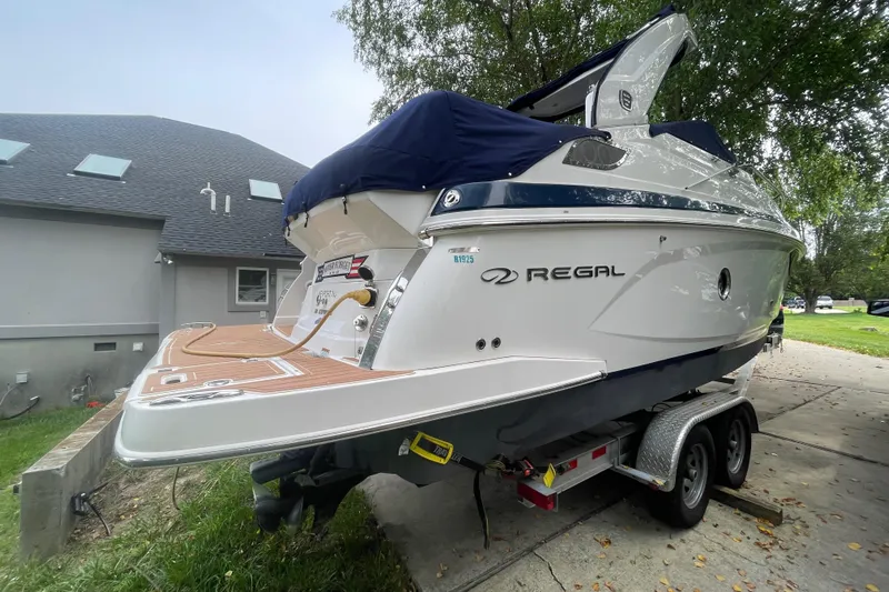  Yacht Photos Pics 2019 Regal 28 Express boat on trailer, parked near a house with trees in the background.