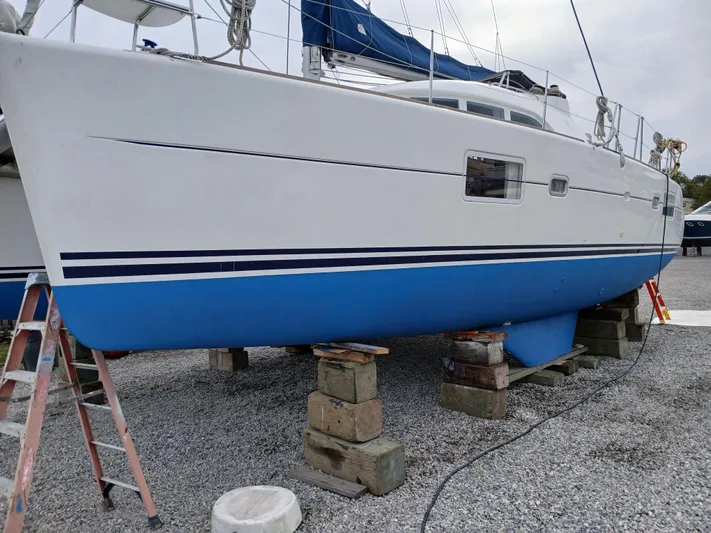 Double Diamond Yacht Photos Pics 2007 Lagoon 380 S2 catamaran on blocks, white and blue hull, outdoor setting.