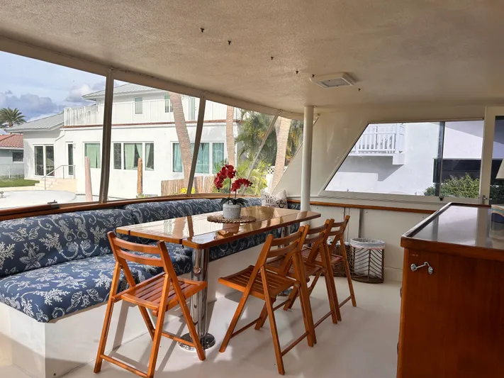 Hatty Shack Yacht Photos Pics Interior of 1989 Hatteras 67 Cockpit Motor Yacht with dining area and wooden chairs.