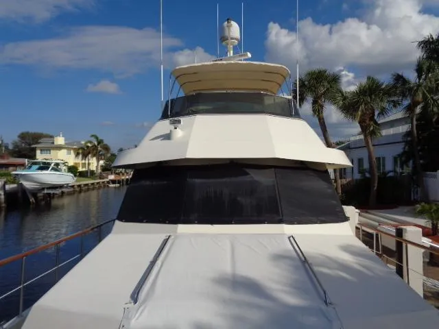 Hatty Shack Yacht Photos Pics 1989 Hatteras 67 Cockpit Motor Yacht docked by palm trees under a blue sky.