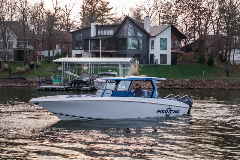  Yacht Photos Pics 2026 Fountain 38 SCX boat cruising on a lake near modern lakeside homes.