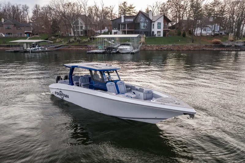  Yacht Photos Pics 2026 Fountain 38 SCX boat cruising on a serene lake near waterfront homes.