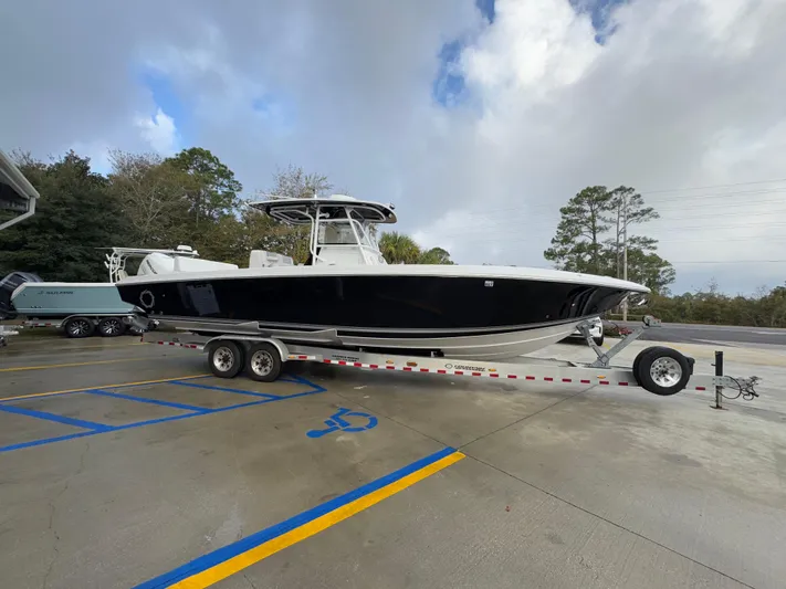  Yacht Photos Pics 2018 Fountain 34 CC boat on trailer in parking lot, cloudy sky background.