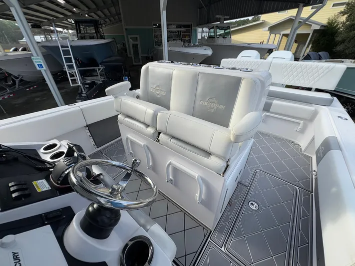  Yacht Photos Pics 2018 Fountain 34 CC boat interior with steering wheel and cushioned seating.