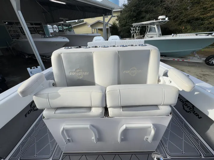  Yacht Photos Pics 2018 Fountain 34 CC boat with cushioned seating and storage, docked outdoors.