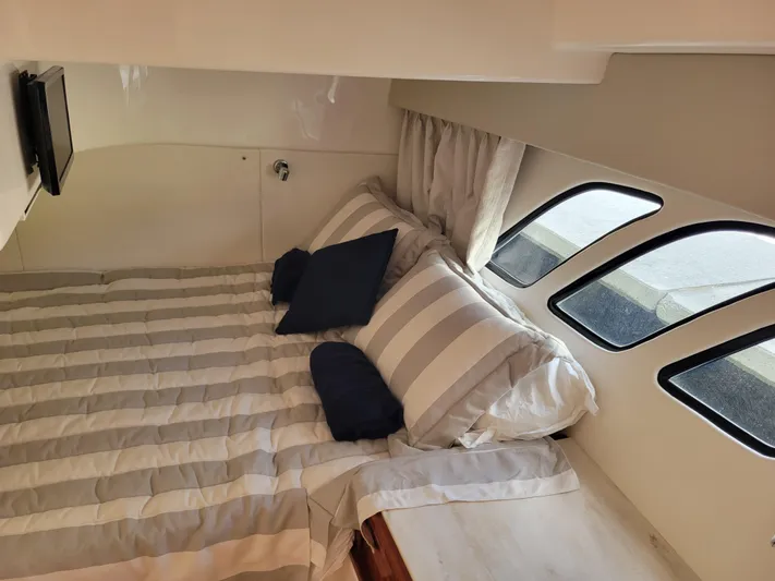  Yacht Photos Pics Cozy cabin interior of 2016 Intrepid 475 Sport Yacht with striped bedding and porthole windows.