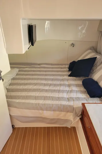 Yacht Photos Pics 2016 Intrepid 475 Sport Yacht cabin with striped bedding and wooden flooring.