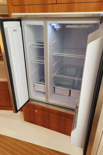  Yacht Photos Pics Open refrigerator inside 2016 Intrepid 475 Sport Yacht, featuring spacious shelves and storage bins.