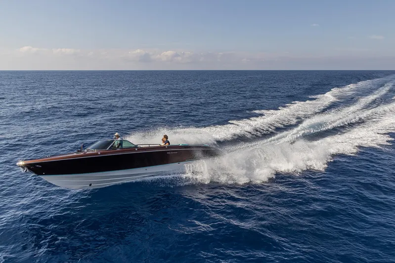 Bacio Yacht Photos Pics 2023 Riva Anniversario speedboat cruising on open sea, leaving a trail of white waves.