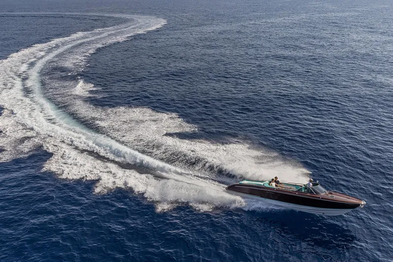 Bacio Yacht Photos Pics 2023 Riva Anniversario speedboat cruising on open water, leaving a dynamic wake trail.