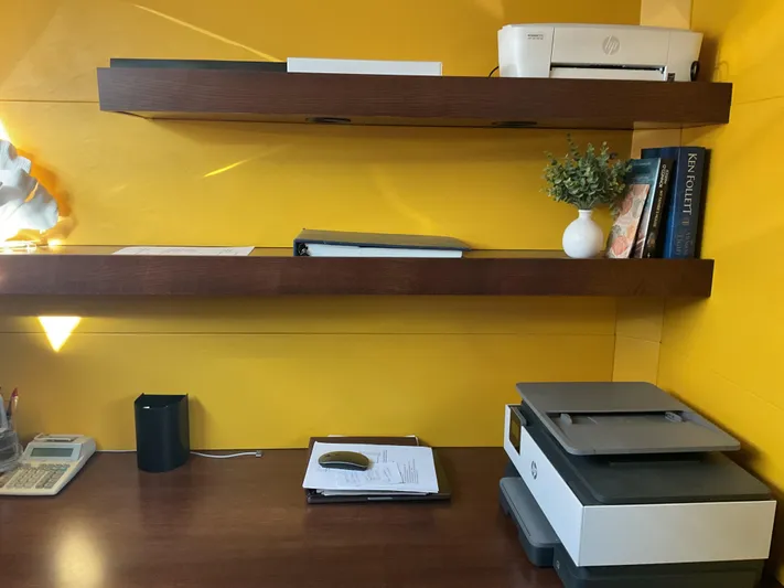 Reflections Yacht Photos Pics Modern office desk with shelves, printer, books, and decor against a vibrant yellow wall.