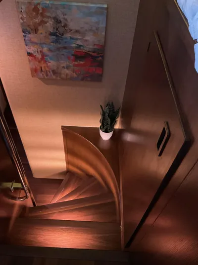 Reflections Yacht Photos Pics Wooden spiral staircase on 1993 Hatteras 60 ED yacht, with abstract painting and potted plant.