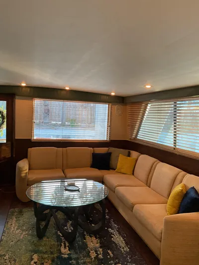 Reflections Yacht Photos Pics Luxurious 1993 Hatteras 60 ED yacht interior with beige sectional sofa and modern glass table.