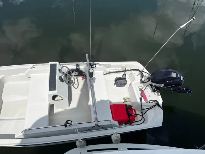 Reflections Yacht Photos Pics Small boat with steering wheel and outboard motor, docked on calm water.