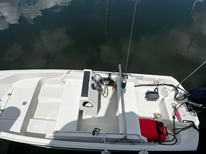 Reflections Yacht Photos Pics Small white boat interior with steering wheel, red fuel tank, and calm water reflection.