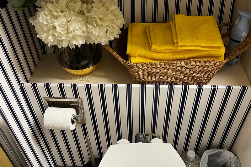 Reflections Yacht Photos Pics Bathroom interior with striped wallpaper, yellow towels, and white flowers on a 1993 Hatteras 60 ED.