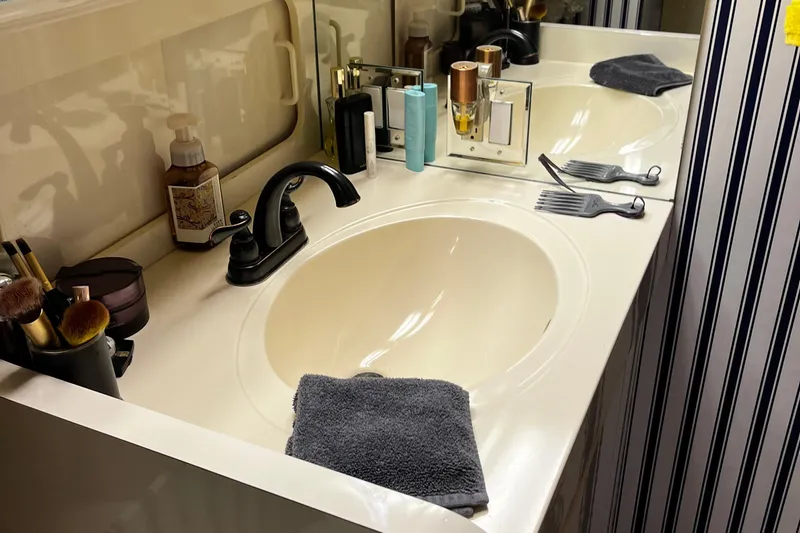 Reflections Yacht Photos Pics Bathroom vanity with dual sinks, toiletries, and striped wallpaper on a 1993 Hatteras 60 ED yacht.