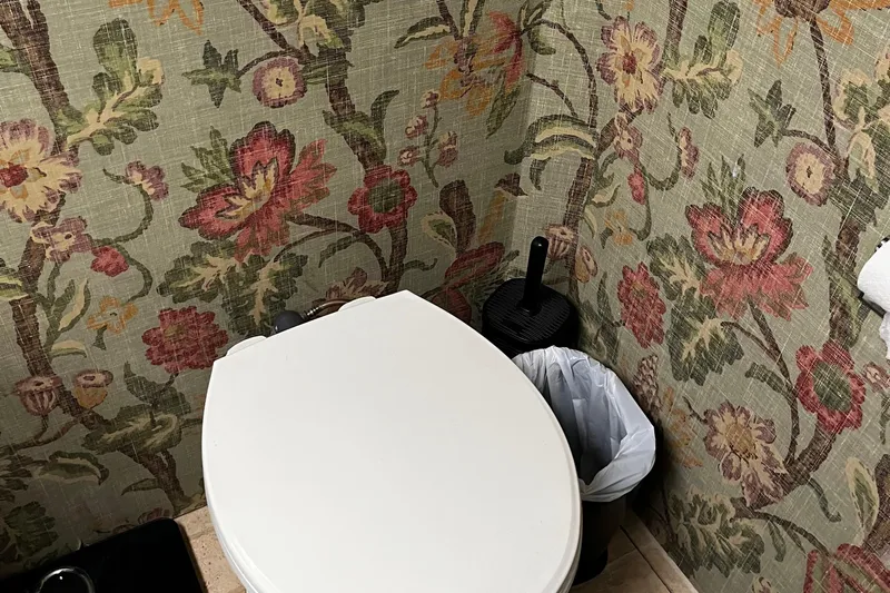 Reflections Yacht Photos Pics Floral wallpapered bathroom with toilet, trash can, and brush on a 1993 Hatteras 60 ED yacht.