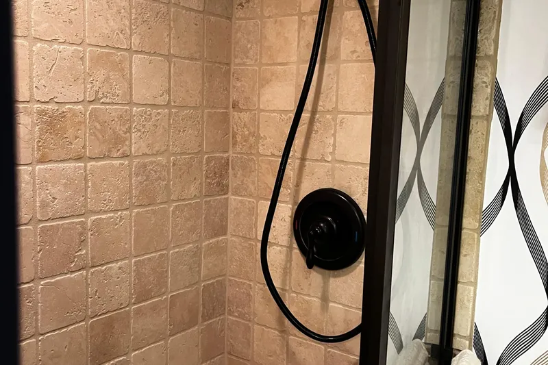 Reflections Yacht Photos Pics Shower area with beige tiles and black fixtures on a 1993 Hatteras 60 ED yacht.