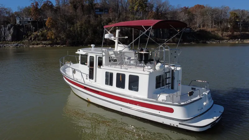  Yacht Photos Pics 2007 Nordic Tug 32 cruising on a calm river with scenic autumn backdrop.