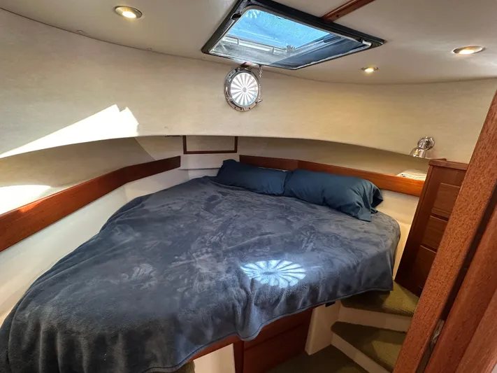  Yacht Photos Pics Cozy cabin interior of 2007 Nordic Tug 32 with skylight and plush bedding.