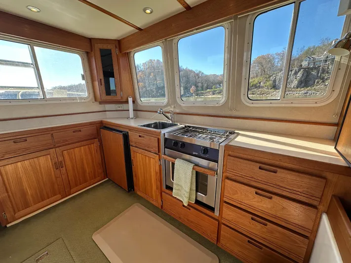  Yacht Photos Pics 2007 Nordic Tug 32 interior kitchen with wooden cabinets and large windows.