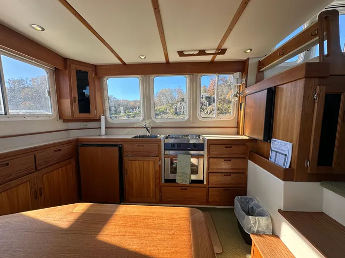  Yacht Photos Pics Interior of 2007 Nordic Tug 32, featuring a cozy kitchen with wooden cabinetry and large windows.