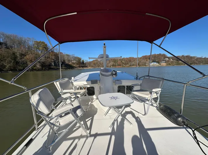  Yacht Photos Pics 2007 Nordic Tug 32 boat deck with chairs and table under red canopy on calm water.